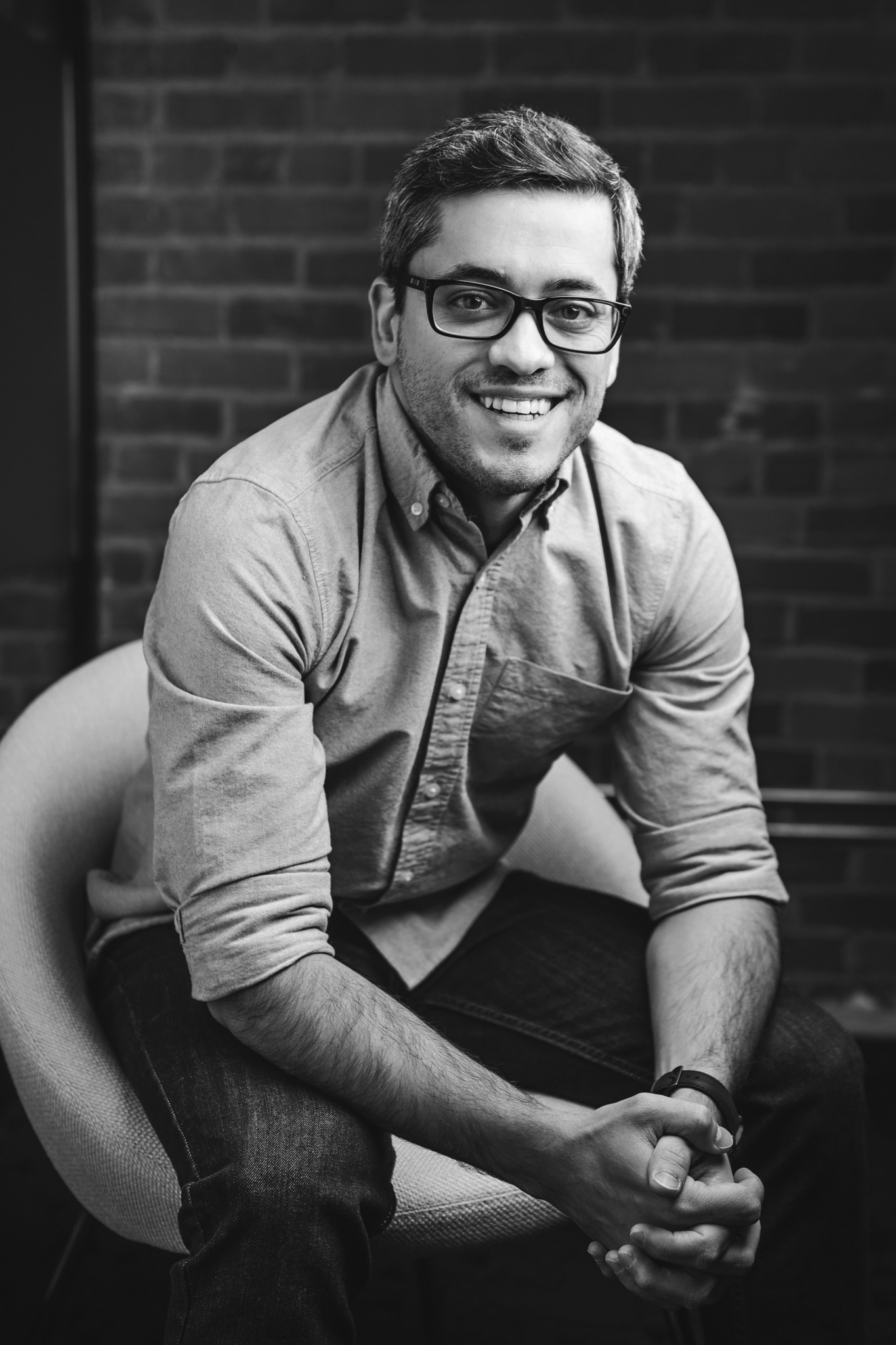 Manoel dos Santos sitting down, looking at the camera and smiling in black and white.